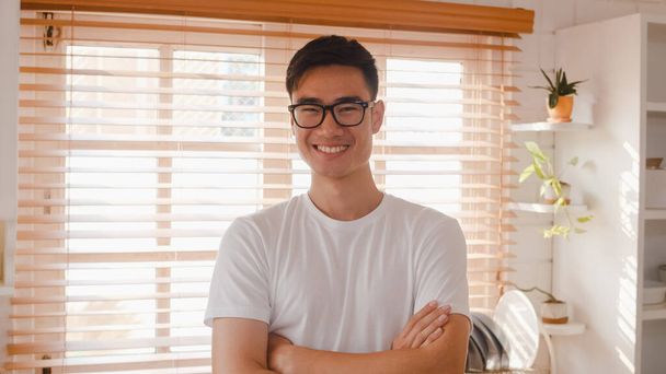 Mutlu genç Asyalı erkek mutlu gülümsüyor, kollarını kavuşturuyor ve mutfakta dinlenirken kameraya bakıyor. Yaşam tarzı adamı ev kavramında. - Fotoğraf, Görsel