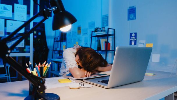 フリーランスアジアは、新しい普通の自宅のオフィスで眠る女性のハードワークを使い果たした。夜間の家の過負荷から働く,リモートで,自己分離,社会的距離,コロナウイルスの予防のための隔離. - 写真・画像
