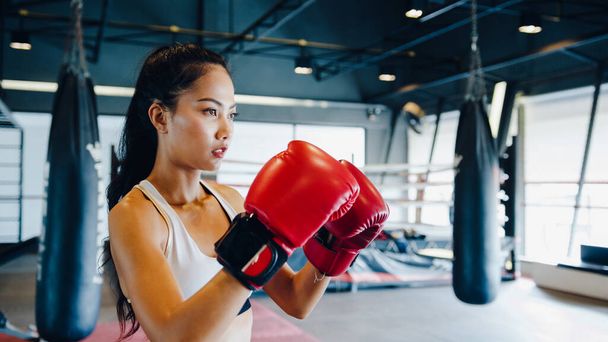 Junge asiatische Kickboxerin übt Workout-Punch, indem sie Schattenkämpferinnen im Fitnessstudio trainiert. Sportlerin Freizeitaktivität, Functional Training, gesundes Lebensstilkonzept. - Foto, Bild