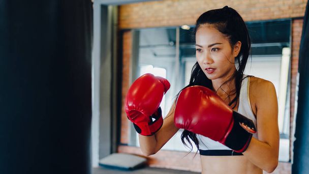 Young Asia lady kickboxing exercise workout punching bag tough female fighter practice boxing in gym fitness class. Sportswoman recreational activity, functional training, healthy lifestyle concept. - Foto, afbeelding