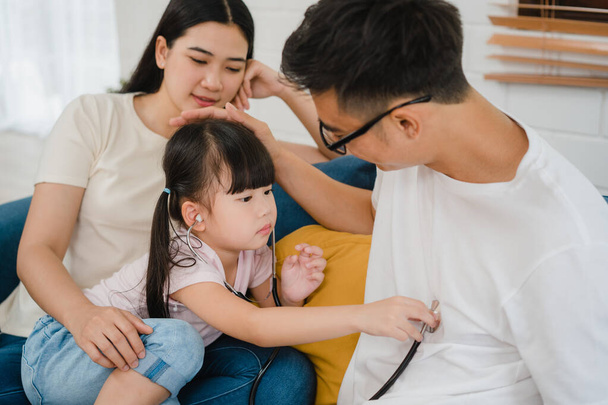 Šťastný veselý asijské rodina táta, maminka a dcera hrát zábavnou hru jako lékař baví na pohovce doma. Sebeizolace, pobyt doma, sociální distancování, karanténa pro prevenci koronaviru. - Fotografie, Obrázek