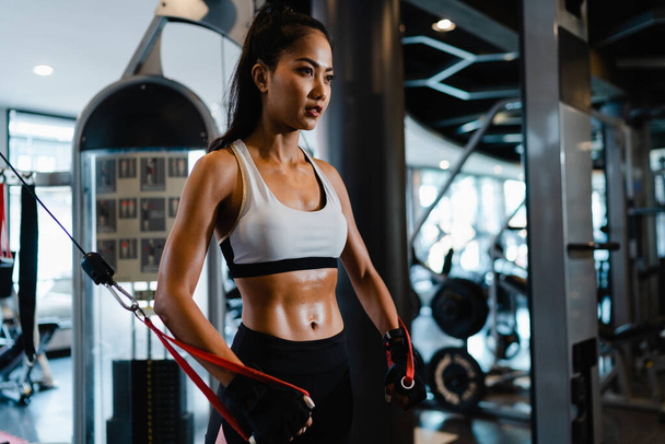 Fiatal ázsiai hölgy testmozgás csinál gyakorló gép Kábel Crossover zsírégető edzés fitness osztályban. Sportoló hat csomaggal, Sportnő szabadidős tevékenység, funkcionális tréning, egészséges életmód. - Fotó, kép