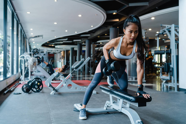 美しい若いアジアの女性の運動は、フィットネスクラスでバーベル脂肪燃焼ワークアウトを持ち上げる。6パック、スポーツ女性レクリエーション活動、機能的なトレーニング、健康的なライフスタイルのコンセプトを持つアスリート. - 写真・画像