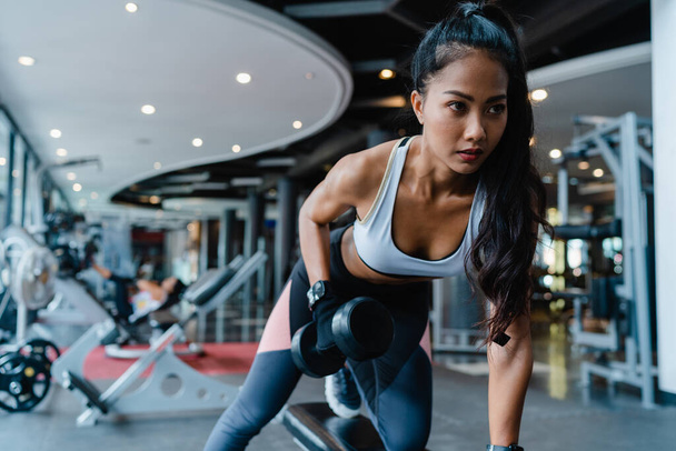 Beautiful young Asia lady exercise doing lifting barbell fat burning workout in fitness class. Athlete with six pack, Sportswoman recreational activity, functional training, healthy lifestyle concept. - Photo, image