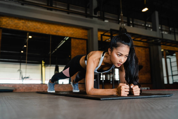 Happy young Asia lady exercise doing plank fat burning workout in fitness class. Athlete with six pack, Sportswoman recreational activity, functional training, healthy lifestyle concept. - Photo, Image