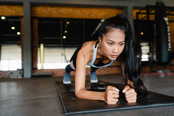 Boldog fiatal ázsiai hölgy testmozgás csinál deszka zsírégető edzés fitness osztályban. Sportoló hat csomaggal, Sportnő szabadidős tevékenység, funkcionális tréning, egészséges életmód koncepció. - Fotó, kép