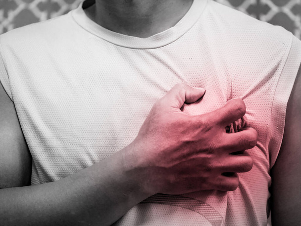 A picture of a man gripping his left chest in pain because of a heart attack. Concept of heart attack symptoms - Valokuva, kuva