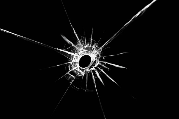 Illustration von Glasscherben mit einem Loch in der Mitte, isoliert auf schwarzem Hintergrund. Die Wirkung von Rissen am Fenster - Foto, Bild