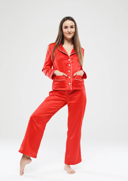 lifestyle, fashion, and people concept - beautiful brunette female dressed in red pajamas over grey background - Foto, imagen
