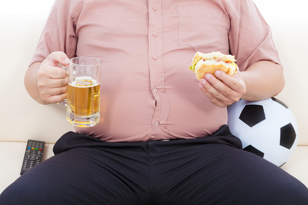 Dicker Geschäftsmann isst Essen und Bier und sitzt auf dem Sofa - Foto, Bild