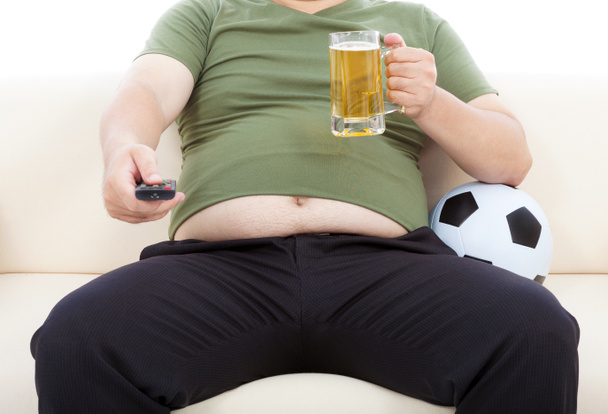 gros homme boire de la bière et assis sur le canapé pour regarder la télévision
 - Photo, image