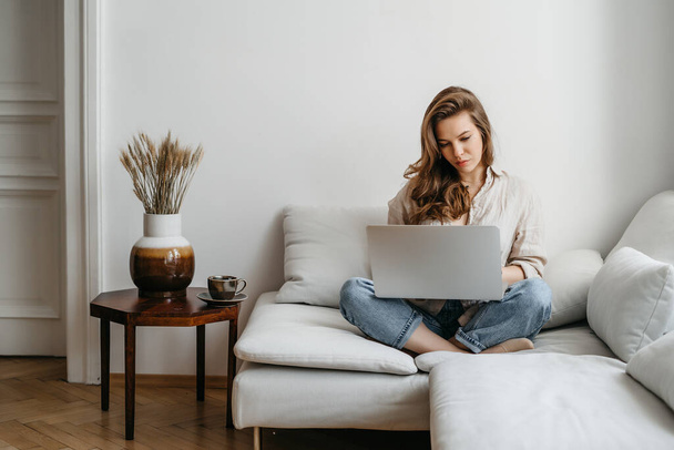 Портрет молодої щасливої фрілансерки, яка сидить на дивані і працює над проектом, дивиться фільм на ноутбуці, вивчає, веде блог, відпочиває і спілкується онлайн
 - Фото, зображення