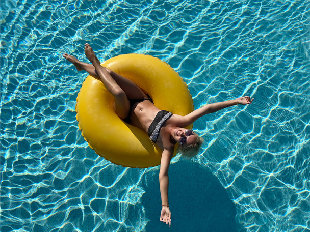 Женщина плавает по кругу в бассейне. Концепция отпуска. Вид сверху - Фото, изображение