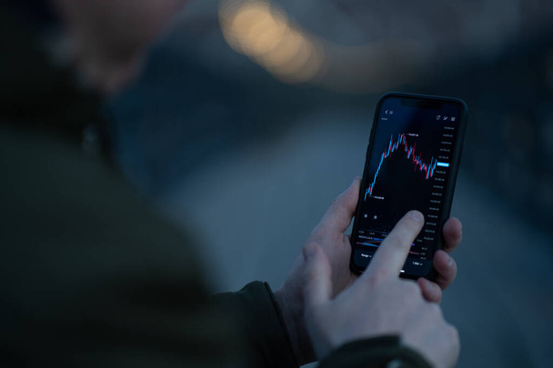Zakenman monitoren voorraad marktgegevens tijdens de handel online in mobiele app - Foto, afbeelding