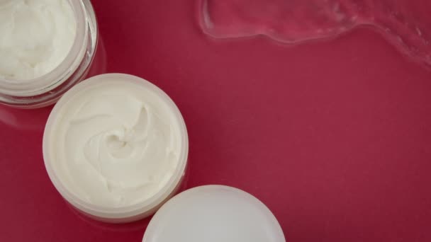Cosmetische potten met hydraterende crème in schoon water spatten op rode achtergrond - Video