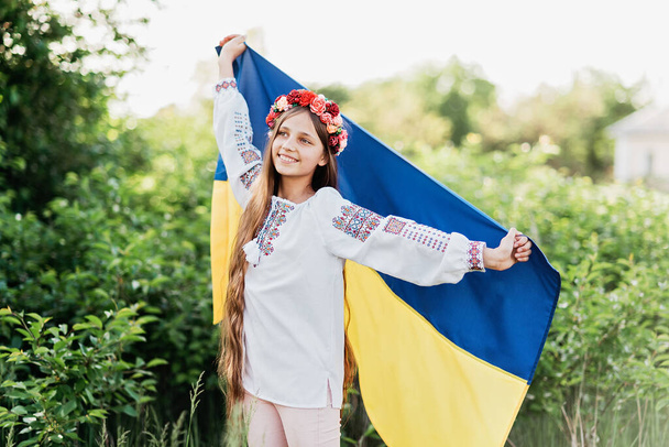 Ukraine's Independence Flag Day. Constitution day. Ukrainian child girl in embroidered shirt vyshyvanka with yellow and blue flag of Ukraine in field. flag symbols of Ukraine. Kyiv, Kiev day - Фото, изображение