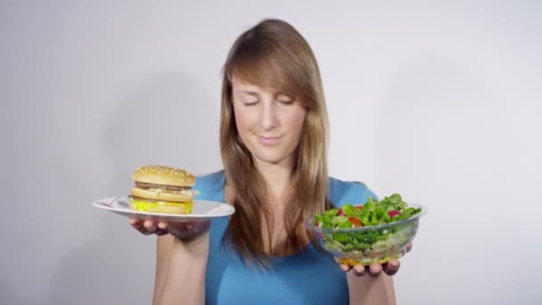 PORTRAIT: Woman chooses a salad over a burger while weighing her lunch options. - Footage, Video