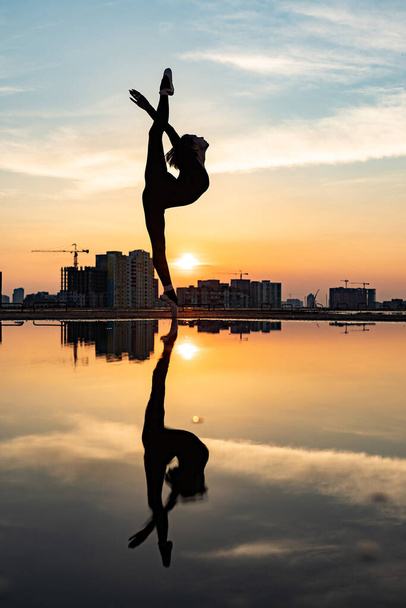 Silhouette of ballerina performing outdoor during sunset. Concept of individuality, creativity and self-confidence - Foto, Imagem