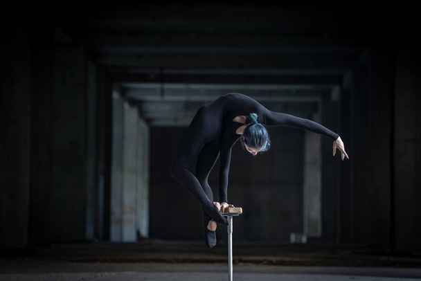 Female flexible circus artist doing handstand in abandoned tunnel. Concept of individuality, creativity and outstanding - 写真・画像