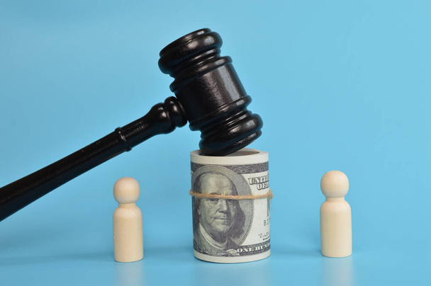 Wooden doll figure standing with judge gavel and money banknote. A court session between businessmen. - Photo, Image