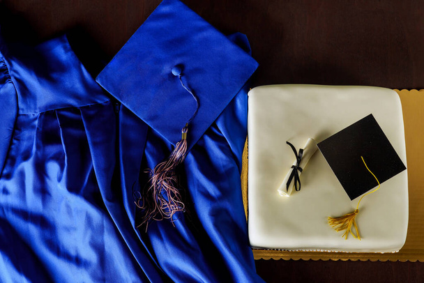 Κάτοψη της αποφοίτησης μπλε καπέλο και φόρεμα με τούρτα για το κόμμα. - Φωτογραφία, εικόνα