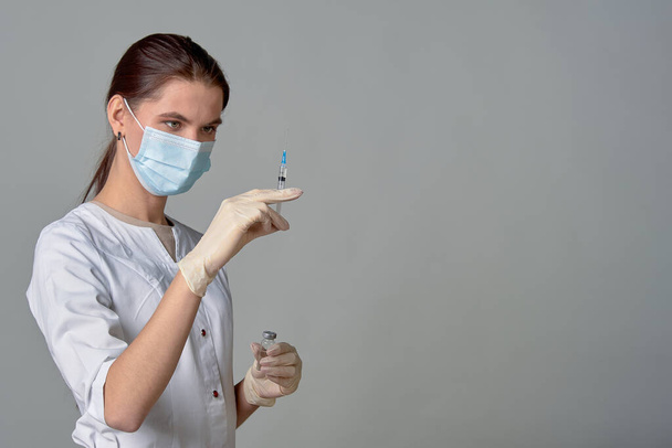 A nurse in a medical mask releases air from a syringe with a vaccine, copy space - Foto, Imagem