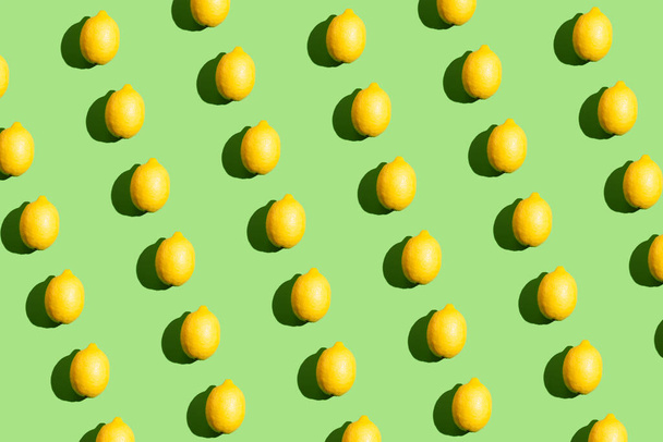 Colorful pop art style repetitive pattern made of lemons with hard shadow on green background - Fotó, kép