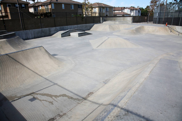 Kilátás szabadtéri üres beton korcsolyapark rámpák és csövek Kaliforniában. A korcsolyaparkok remek hely a gyerekeknek, hogy trükköket csináljanak, és gyakorolják a görkorcsolyázást és a korcsolyázást. Szórakozás minden korosztálynak. Korcsolyapark Szórakozás. - Fotó, kép