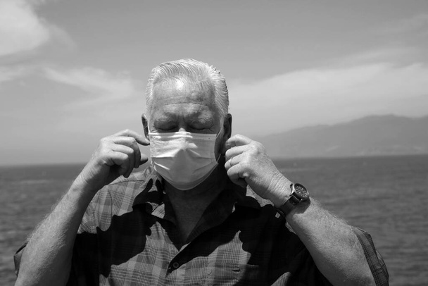 Чоловік у паперовій масці на обличчі. Чоловік носить медичну маску, щоб не заразитися коронавірусом, який називається Ковід-19. Ковід-19 - це хвороба повітряного десанту, яка поширилася по всьому світу. Надень маску, спаси жизнь. Ковід-19 Постер. Чорний і білий.  - Фото, зображення