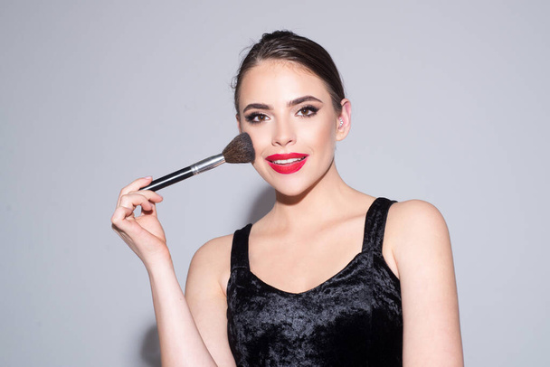 Beautiful girl model with natural makeup putting blush with cosmetic brush. - Zdjęcie, obraz