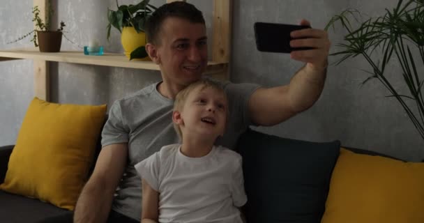 Padre e hijo hablan por enlace de video. Un hombre y un niño graban el video en su teléfono. Llame a sus seres queridos desde casa - Metraje, vídeo
