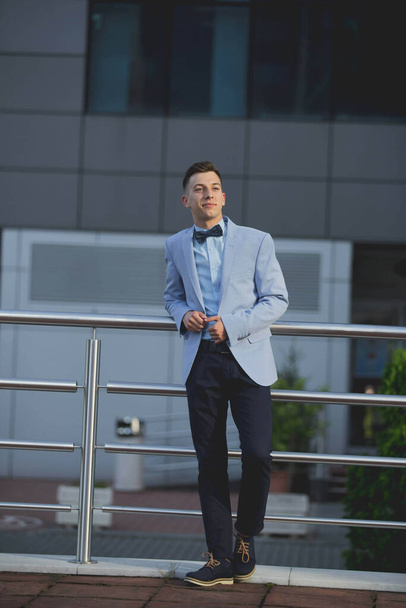 A vertical shot of a young male model posing in a light blue suit and a bow tie - Foto, imagen