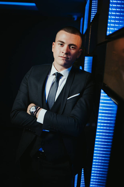 A vertical shot of a young attractive male in a formal suit posing in a nightclub - Фото, зображення