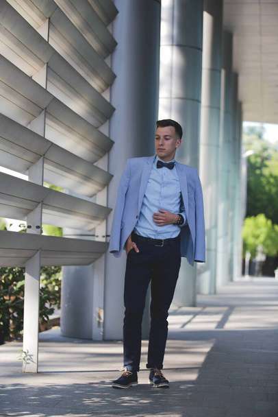 A vertical shot of a handsome Bosnian Caucasian man in a suit and bow tie, posing outdoors - Fotoğraf, Görsel
