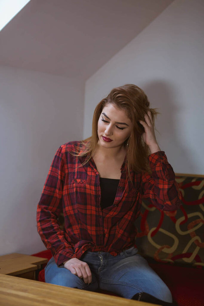 A caucasian young female with a plaid red t-shirt at home - Фото, изображение