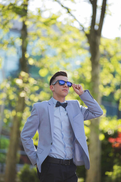 A vertical shot of a young male model posing in a light blue suit and a bow tie - Zdjęcie, obraz