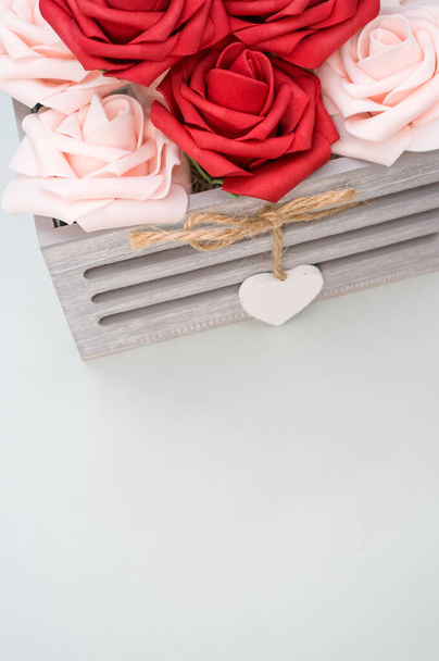 A vertical shot of beautiful red and white roses in a box isolated on a grey background - Photo, image