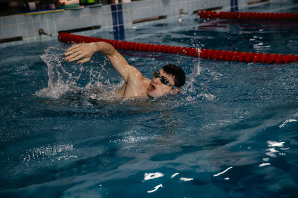 mannelijke zwemmer, vrije stijl zwemmen op de baan in het overdekte zwembad - Foto, afbeelding