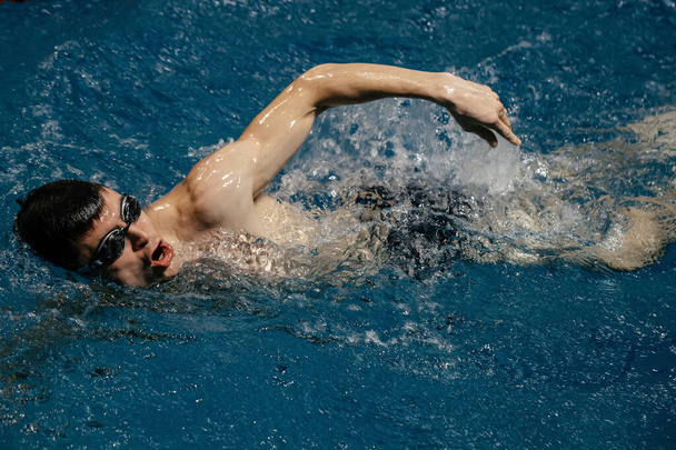 nadador humano, un joven atleta deportivo nada en estilo libre en el agua azul azur en la piscina - Foto, Imagen