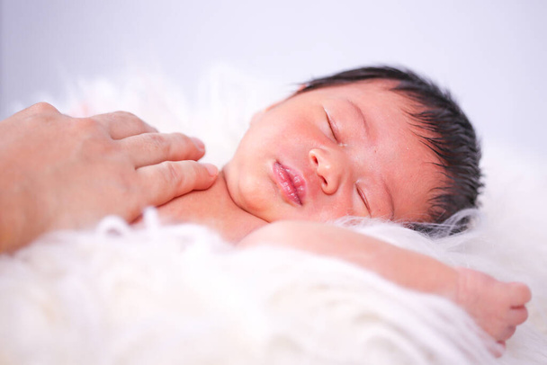 赤ん坊の女の子は柔らかいマットレスの上に横たわっている。赤ん坊はマットレスの上で泣いている. - 写真・画像