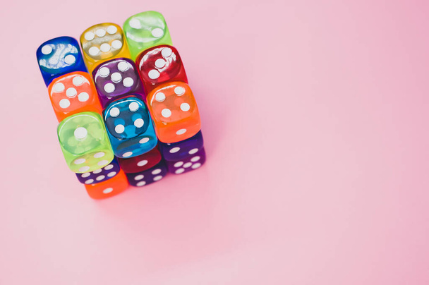 A cube made of colorful dice isolated on a pink background - Foto, imagen