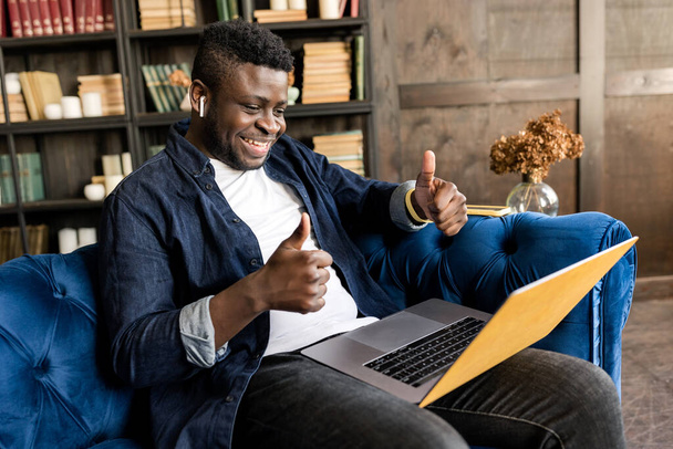 african american man with laptop showing thumbs up  - 写真・画像
