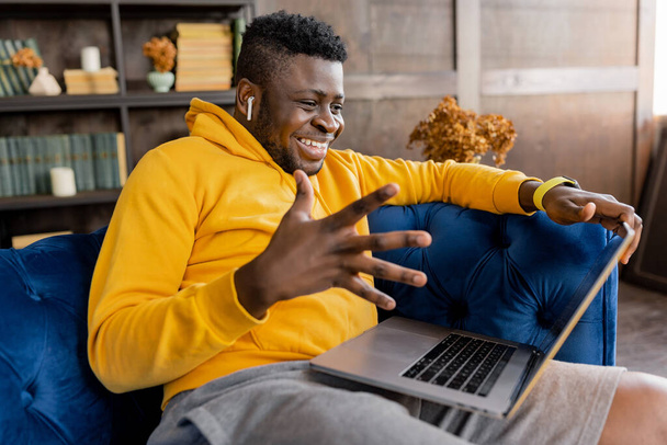 african american man with laptop on sofa at home - Foto, Bild