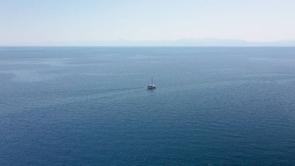 Increíble toma aérea en mar abierto con vistas a un barco blanco navegando en el mar Egeo, Grecia. - Foto, imagen