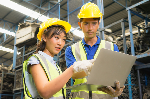 Жінка і чоловік працюють разом, різноманітність азіатських інженерів-робітників і чоловік дивляться на екран на ноутбуку на складі фабрики. - Фото, зображення