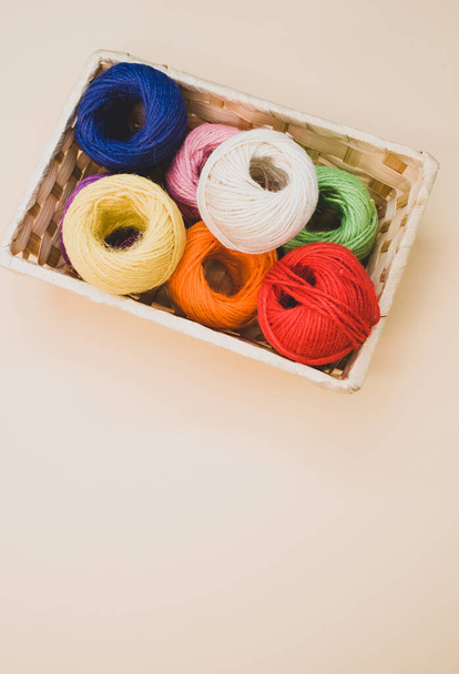 A vertical shot of colorful thread rolls in a box isolated on a beige background - Zdjęcie, obraz