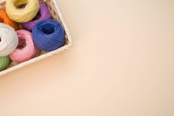 Colorful thread rolls in a box isolated on a beige background - Фото, изображение