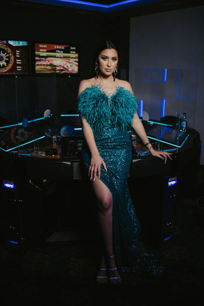A vertical shot of a young attractive female in an elegant sexy dress posing in a casino - Fotó, kép