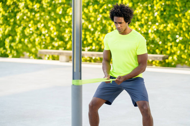 Hombre negro haciendo ejercicio con banda elástica al aire libre - Foto, Imagen