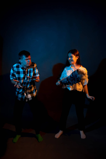 A guy in a plaid shirt and a girl with a dust brush against a dark background - 写真・画像